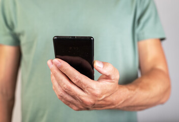 Man holding phone for checking social media, surfing Internet, looking through photos and news articles. Male hands with smartphone closeup