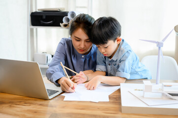 Little kid son practicing pencil drawing and writing under mother's control, While Young Asian mother is an architect spending time with her little kid son, Mother helping son, Homeschool concept