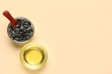 Bowls with sunflower oil and seeds on color background