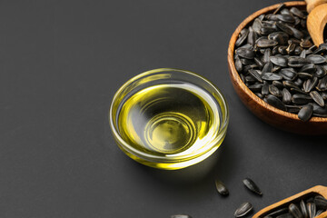 Bowls with oil and sunflower seeds on black background, closeup