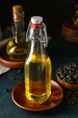 Glass bottle of sunflower oil on dark background, closeup