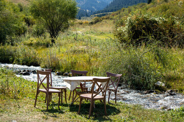 wooden table and chairs by the mountain river