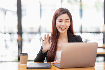 Young attractive Freelancer business asian woman talking about sale report in video call conference on laptop computer online meeting in the workplace, finance Work remotely Social isolation concept.