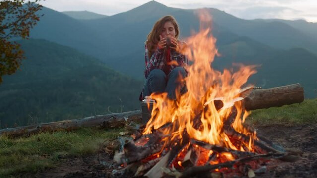 Closeup relaxed woman camping on nature. Tourist look bonfire in mountains trip.