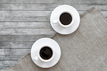two white cups of black coffee on a gray surface, top view, flatley