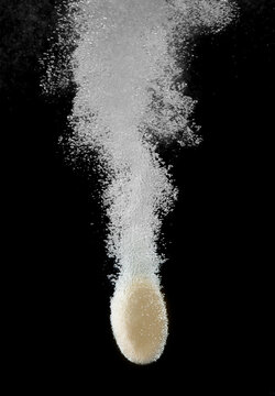 effervescent tablet dissolving in water against a black background