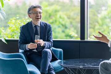 ロビーでシャンパンを飲みながら談笑するエグゼクティブ男性