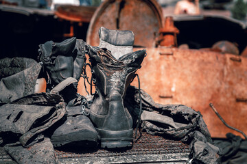 Fragments of burnt boots and clothes of a Russian soldier on a wrecked armored vehicle in the war...