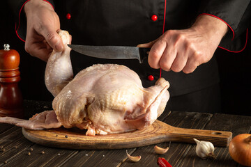 Experienced chef cuts raw chicken with a knife in the kitchen. Cooking chicken for lunch