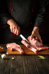 The cook cuts raw ribs on a cutting board before preparing a meat dish. Hotel Recipe Idea.