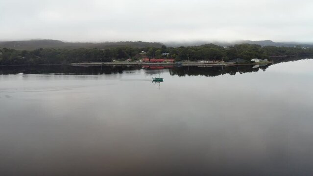 Aerial: Drone flying around a fishing boat on a large lake in Strahan Tasmania, Australia