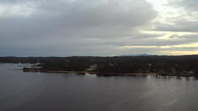 Aerial: Drone flying towards a harbour of boats during a moody overcast morning in Tasmania