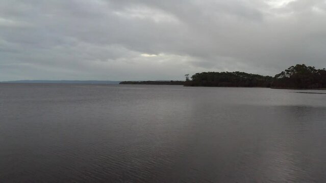 Aerial: Drone flying over a large lake on a moody overcast day on the West Coast of Tasmania