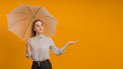 young girl teenager with a white umbrella looks up and stands on a yellow background with copy space