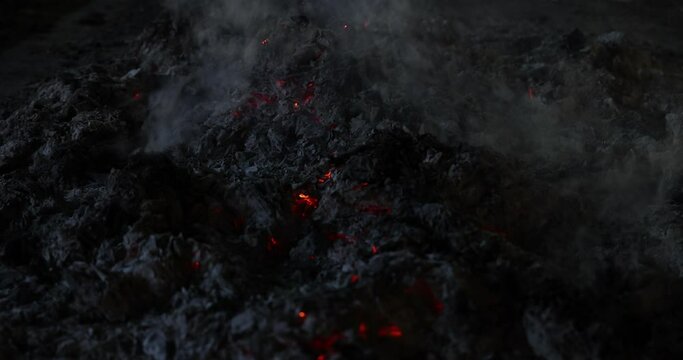 Burnt dark paper ash flame smoke amber glowing under pile blowing wind at night