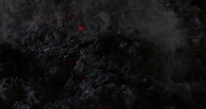 Burnt dark paper ash flame smoke amber glowing under pile blowing wind at night