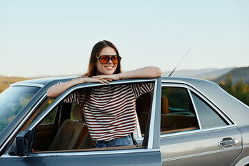 A young woman driver looks out of the car at the autumn landscape and smiles satisfactorily