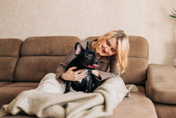Woman holding a french bulldog puppy on her hands cute lovely moment of dog lover owner. Happy pet living in the apartment