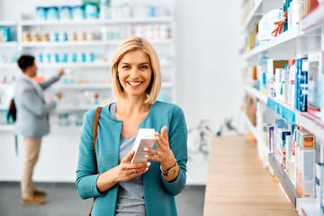 Foto auf Acrylglas Apotheke Happy woman buying in pharmacy and looking at camera.