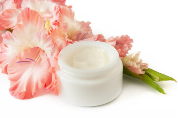 Obraz na płótnie Canvas cosmetic cream and gladiolus flowers bunch on white background. Organic cosmetic concept. Natural cosmetic cream with flower extract