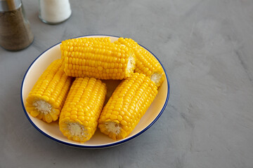 Homemade Steamed Corn on the Cob with Butter on a Plate, side view. Space for text.