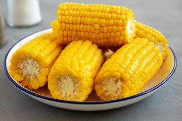 Homemade Steamed Corn on the Cob with Butter on a Plate, side view. Close-up.