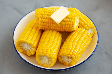 Homemade Steamed Corn on the Cob with Butter on a Plate, side view. Close-up.