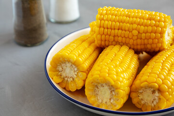 Homemade Steamed Corn on the Cob with Butter on a Plate, side view. Close-up.