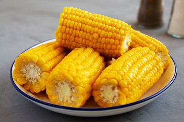 Homemade Steamed Corn on the Cob with Butter on a Plate, side view. Close-up.