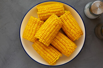 Homemade Steamed Corn on the Cob with Butter on a Plate, top view. Flat lay, overhead, from above.