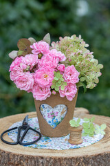 Blumenstrauß mit pink Rosen und Hortensien-Blüten im Torftopf mit Herzmotiv