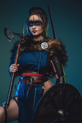 Photo of nordic huntress woman with strup back longbow holding shield and axe. - obrazy, fototapety, plakaty