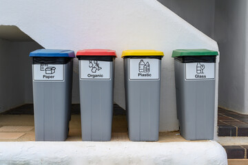 Four recycling garbage cans, reading: paper, organic, plastic and glass.