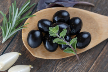 olives with spices and rosemary in a wooden spoon