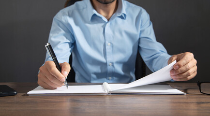 Businessman writing on a notepad in office.