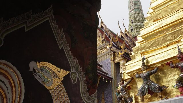 A beautiful wall painting of a dragon with the impressive golden Grand Palace in the background in the city of Bangkok