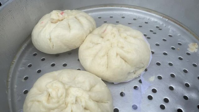 For sale in the street of TIRETTA BAZAR, Kolkata, are several Bao that have been loaded with succulent pork and chicken and steamed in a stainless steamer.