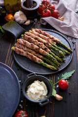 Healthy food - Asparagus wrapped with bacon and spices on a plate on wooden table