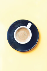 Cup of coffee on yellow background. Top view. Copy space.