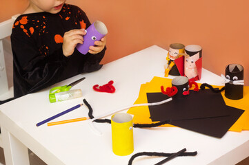 Boy and girl in costume make craft for Halloween. Toilet paper roll reuse vampire, bat, monsters...