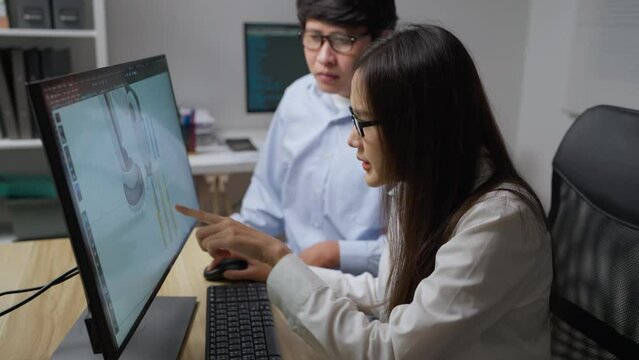 Asian developer working at office. They are trying to develop robot arm together. Technology and Development concept.