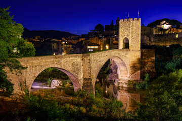 Obraz premium Medieval bridge that crosses the river in the ancient city of Besalu at night, Gerona, Spain.