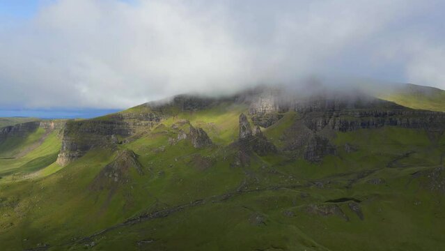 Aerial fly over above the Old man of Stor on the Isle of skye through the clouds with sunbursts during sunris
