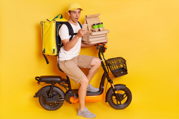 Shocked courier on electric scooter with thermo backpack delivering pizza and coffee to go, holding...