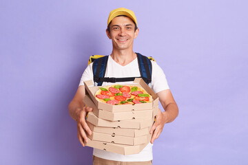 Portrait of happy young deliveryman standing with pizza box and looking smiling at camera, fast...
