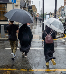 London. UK- 08.25.2022. Pedestrians on the street during heavy rain storm after record drought and...