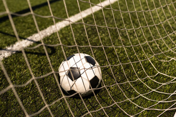 white and black soccer ball on green grass and stadium background. sports betting idea.
