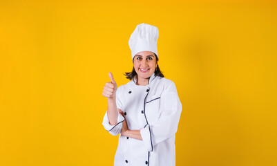 Hispanic woman chef  with thumbs up and copy space on yellow background in Mexico latin America	