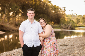 Girlfriend cuddling into boyfriends arm standing near water smiling