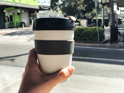 Close Up Shot Of A Black And White Mug With A Hand Facing An Empty Road